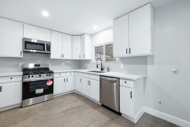 kitchen with sink, light hardwood / wood-style flooring, stainless steel appliances, and white cabinets