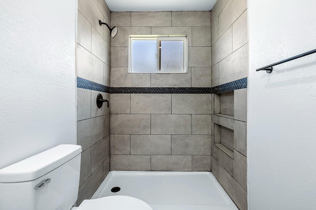 bathroom featuring tiled shower and toilet