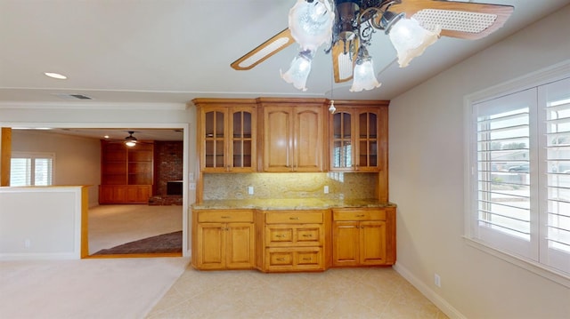 kitchen with ceiling fan, light stone counters, and a wealth of natural light