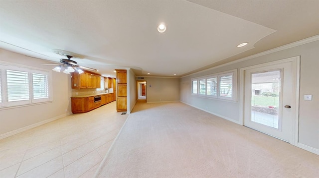 unfurnished living room featuring ceiling fan, light colored carpet, crown molding, and a wealth of natural light