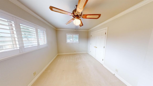 carpeted empty room featuring ceiling fan and crown molding