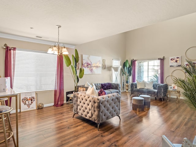 living room featuring a chandelier, a textured ceiling, crown molding, and dark hardwood / wood-style flooring