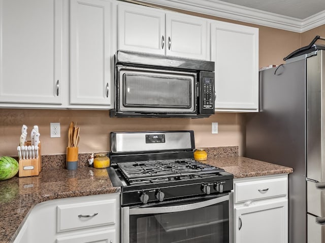 kitchen featuring gas stove, dark stone counters, and white cabinets