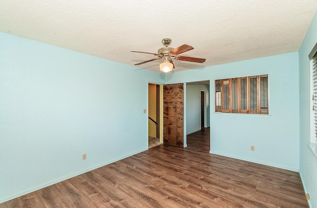 empty room featuring ceiling fan, dark wood-type flooring, and a textured ceiling