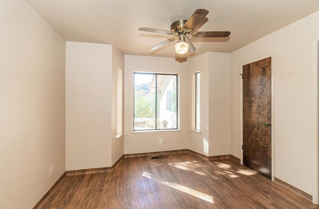 spare room with dark hardwood / wood-style flooring and ceiling fan