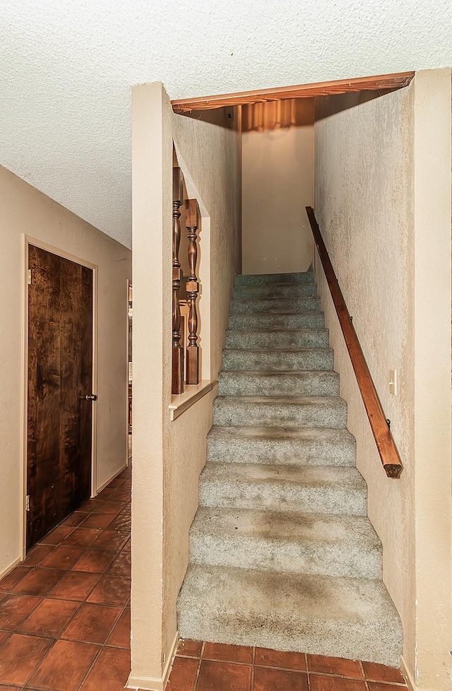 stairs featuring tile patterned flooring and a textured ceiling