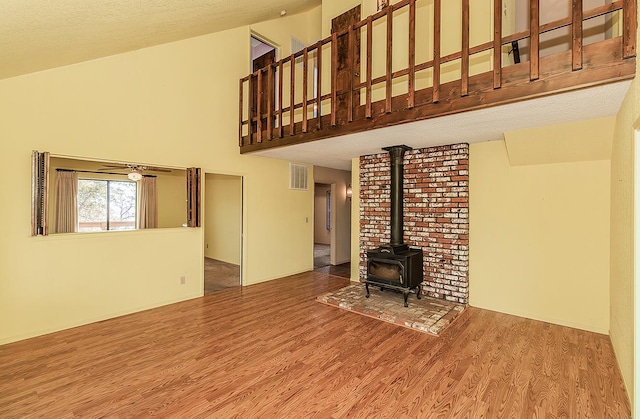 unfurnished living room with a wood stove, a textured ceiling, and hardwood / wood-style flooring