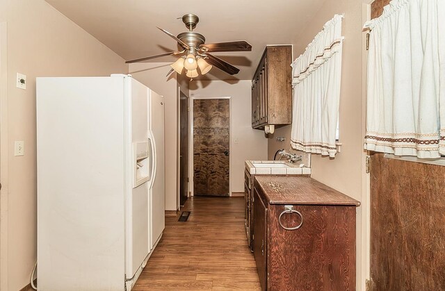 kitchen with light hardwood / wood-style floors, white refrigerator with ice dispenser, ceiling fan, dark brown cabinetry, and sink