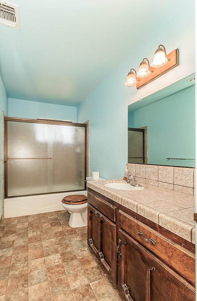 full bathroom with shower / bath combination with glass door, vanity, and toilet