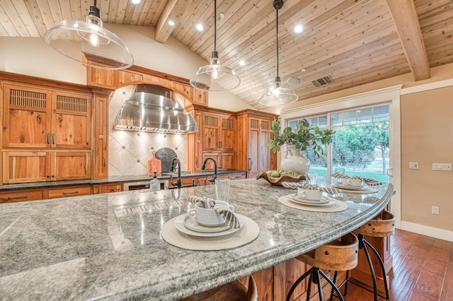 kitchen featuring dark stone counters, lofted ceiling with beams, dark wood-type flooring, and pendant lighting