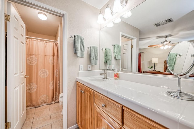 bathroom featuring curtained shower, vanity, tile patterned flooring, ceiling fan, and toilet