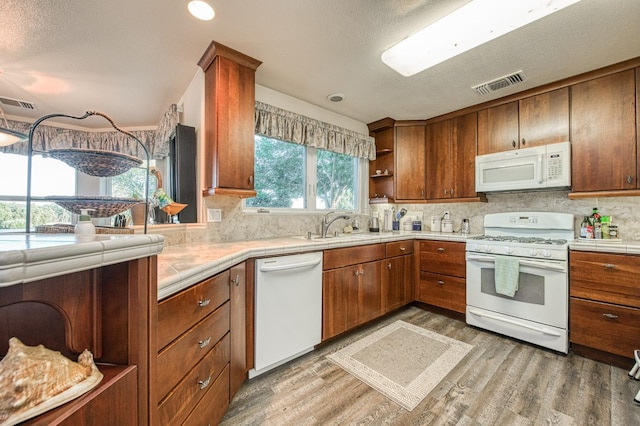 kitchen featuring light hardwood / wood-style floors, a textured ceiling, white appliances, and tasteful backsplash