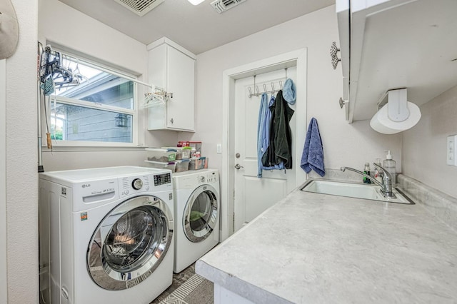 clothes washing area with sink, independent washer and dryer, and cabinets