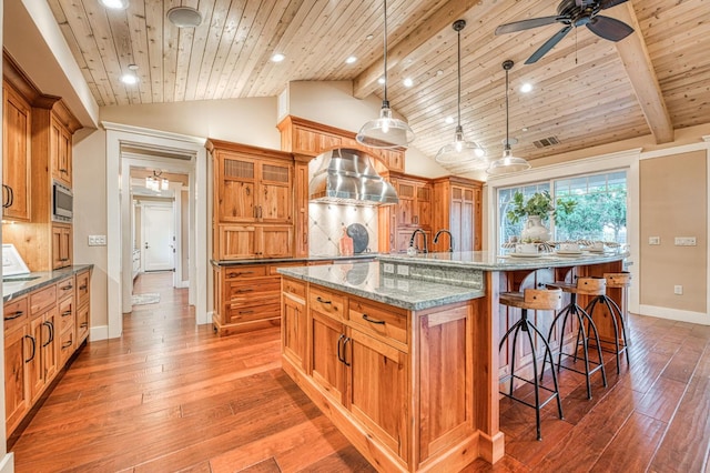 kitchen with ceiling fan, pendant lighting, beamed ceiling, wood-type flooring, and a large island