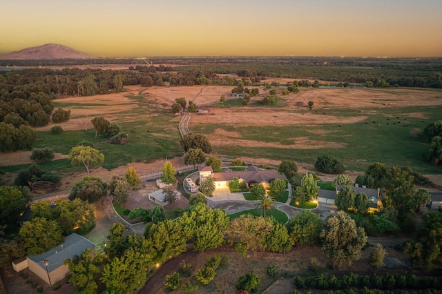 aerial view at dusk featuring a mountain view and a rural view