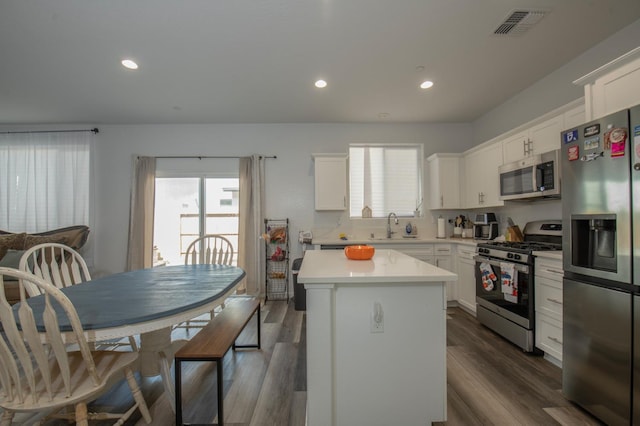 kitchen with white cabinetry, a center island, stainless steel appliances, and dark hardwood / wood-style floors