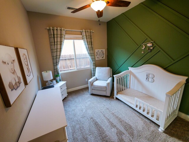 bedroom with a crib, carpet floors, and ceiling fan