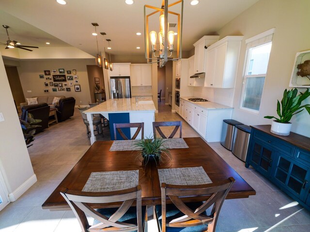 dining space with ceiling fan with notable chandelier and light tile patterned floors