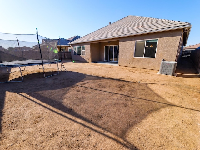 rear view of house featuring central AC and a trampoline