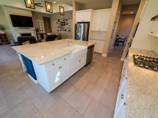 kitchen featuring decorative light fixtures, stainless steel appliances, an island with sink, and white cabinets