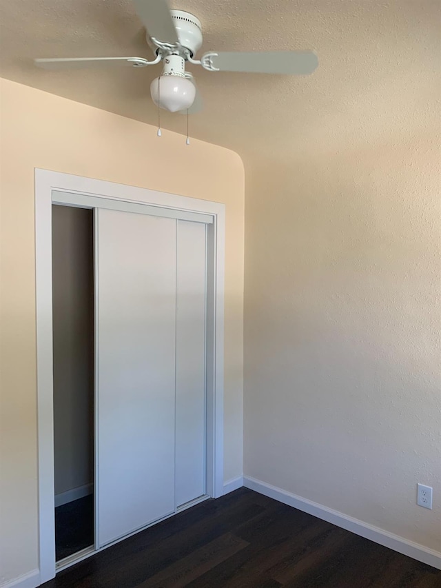 interior space with dark hardwood / wood-style floors, ceiling fan, and a closet