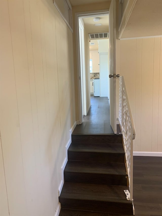 stairway featuring wooden walls and hardwood / wood-style floors