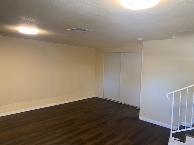 empty room featuring a textured ceiling and dark hardwood / wood-style flooring