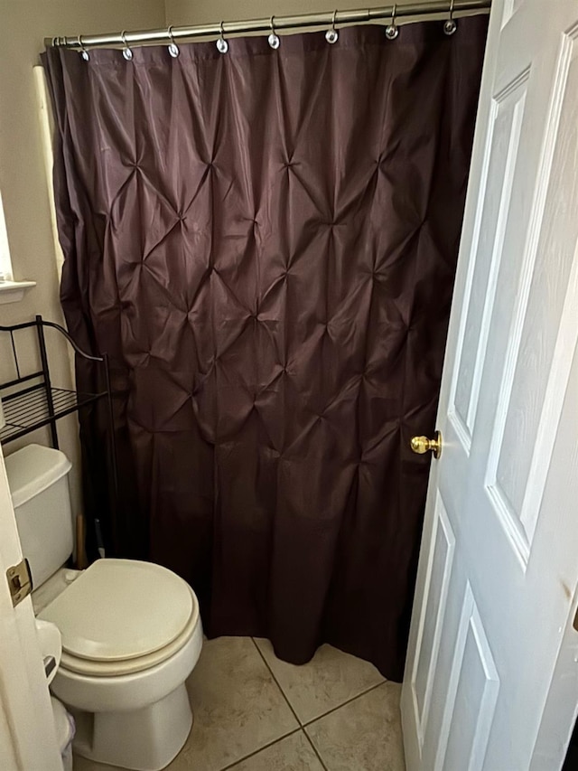 bathroom with a shower with curtain, toilet, and tile patterned floors