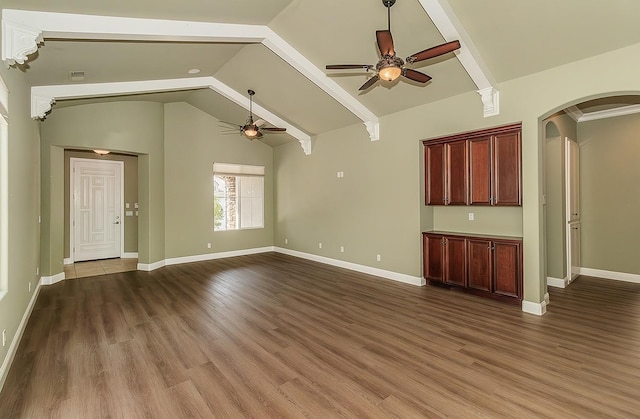 unfurnished living room with arched walkways, ceiling fan, wood finished floors, baseboards, and vaulted ceiling