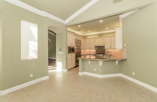 kitchen featuring tasteful backsplash, crown molding, a peninsula, and built in appliances