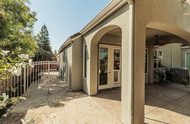 view of side of property with central AC, fence, french doors, stucco siding, and a patio area