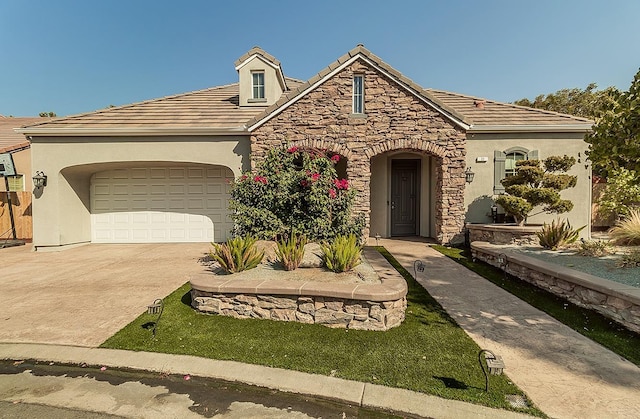 view of front of property with a tile roof, stucco siding, an attached garage, stone siding, and driveway