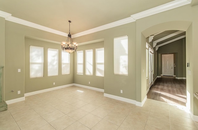 spare room with arched walkways, ornamental molding, light tile patterned flooring, a chandelier, and baseboards