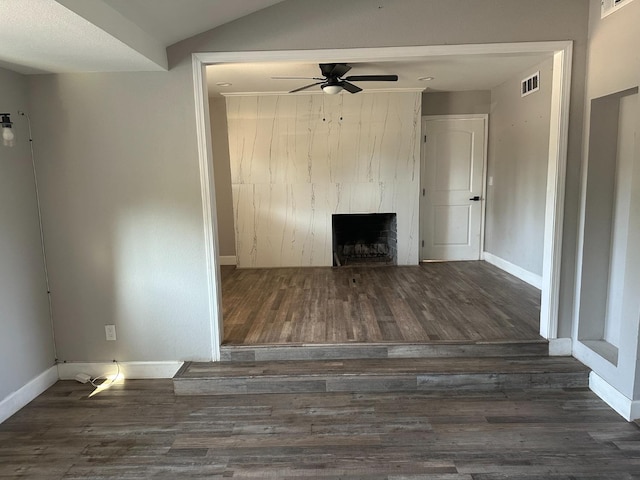 unfurnished living room featuring ceiling fan, a large fireplace, and dark hardwood / wood-style floors