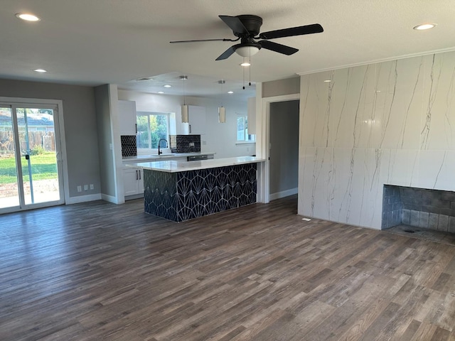 kitchen with a healthy amount of sunlight, white cabinetry, hanging light fixtures, and dark wood-type flooring