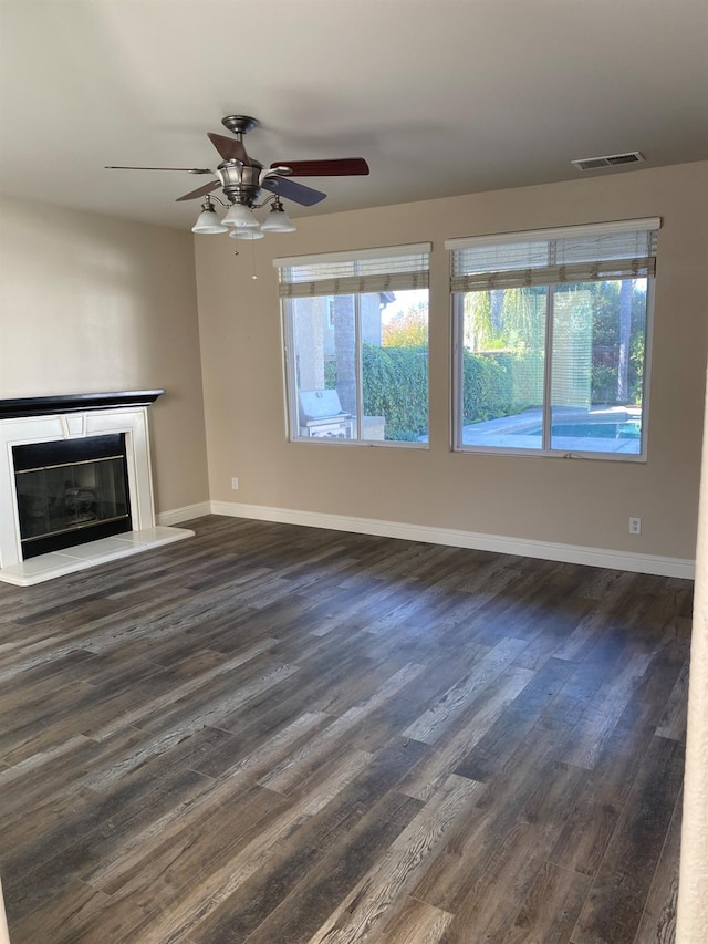 4707 N Arrow Ridge Way N, Clovis, CA 93619 - unfurnished living room featuring dark wood finished floors, healthy amount of natural light, a ceiling fan, and a glass covered fireplace