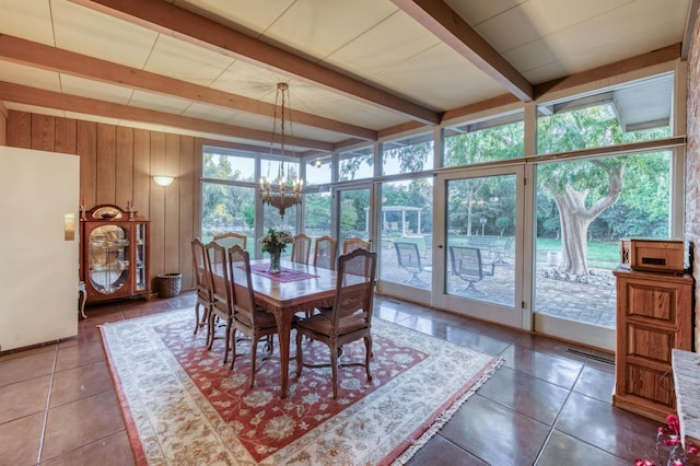 dining space with an inviting chandelier, floor to ceiling windows, wood walls, dark tile patterned flooring, and beamed ceiling