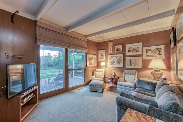 living room with carpet floors, beam ceiling, and wooden walls