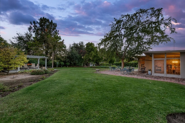 yard at dusk featuring a pergola