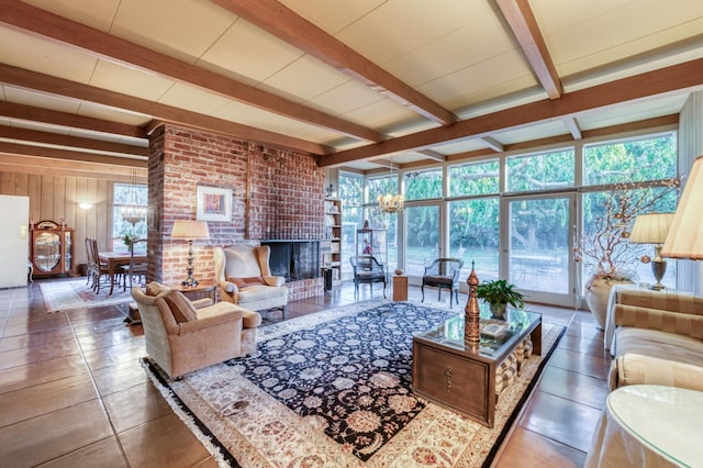 living room featuring beam ceiling, a brick fireplace, dark tile patterned floors, and a chandelier