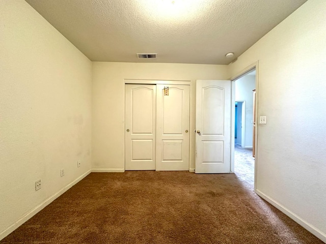 unfurnished bedroom featuring dark colored carpet, a closet, and a textured ceiling