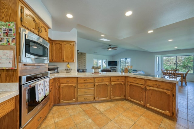 kitchen featuring lofted ceiling, kitchen peninsula, appliances with stainless steel finishes, and ceiling fan