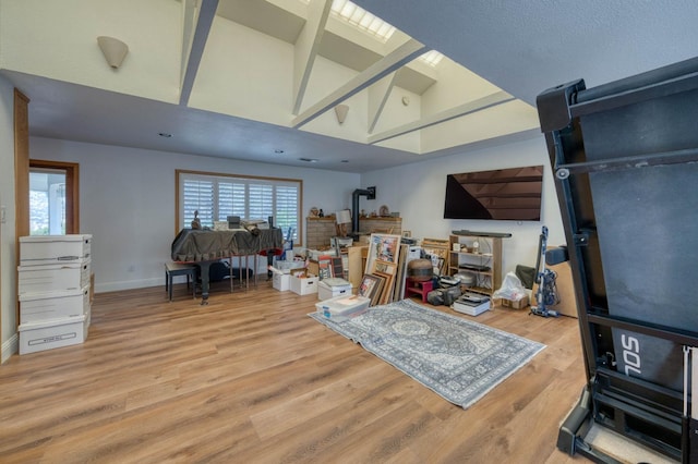 interior space featuring hardwood / wood-style floors, beamed ceiling, a skylight, and high vaulted ceiling