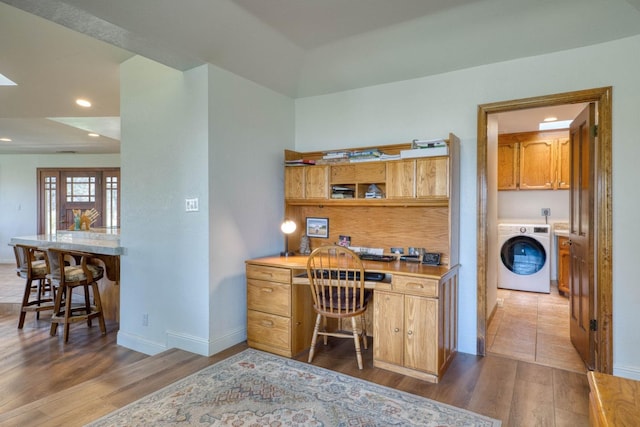 office featuring built in desk, washer / dryer, and dark hardwood / wood-style flooring