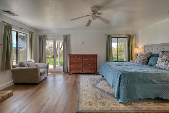 bedroom with ceiling fan, wood-type flooring, access to exterior, and multiple windows