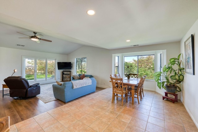 living room featuring lofted ceiling, light hardwood / wood-style floors, ceiling fan, and plenty of natural light