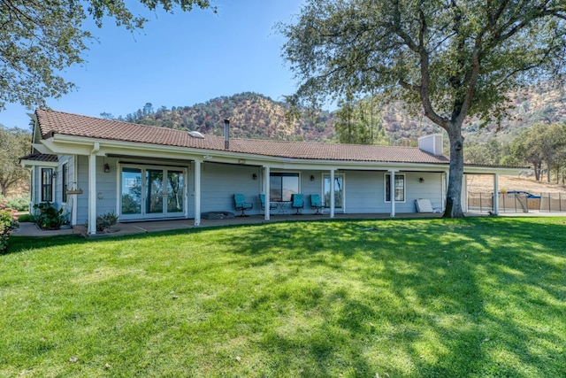 rear view of house with a mountain view and a lawn