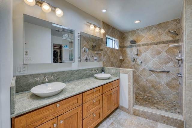 bathroom with a tile shower and vanity