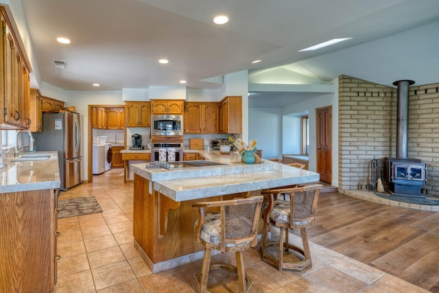 kitchen with a wood stove, stainless steel appliances, kitchen peninsula, and a breakfast bar area