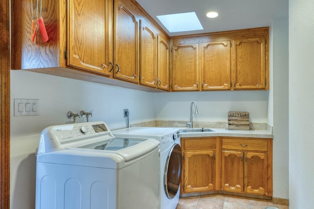 laundry area featuring cabinets, sink, a skylight, light tile patterned floors, and washer and clothes dryer